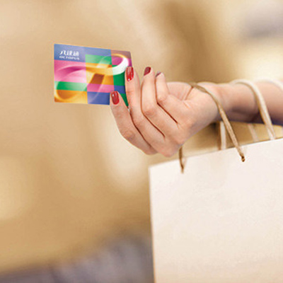 a lady’s hand holding an octopus card and paper shopping bag