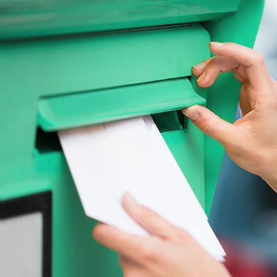 a person putting letters into a green postbox