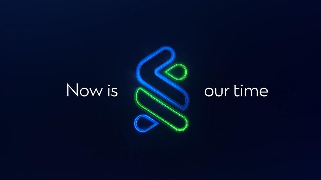 The Standard Chartered trust mark in blue and green neon light, surrounded by the words 'Now is our time.'