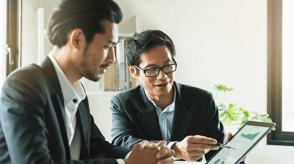 Two Asian men looking at charts on a tablet