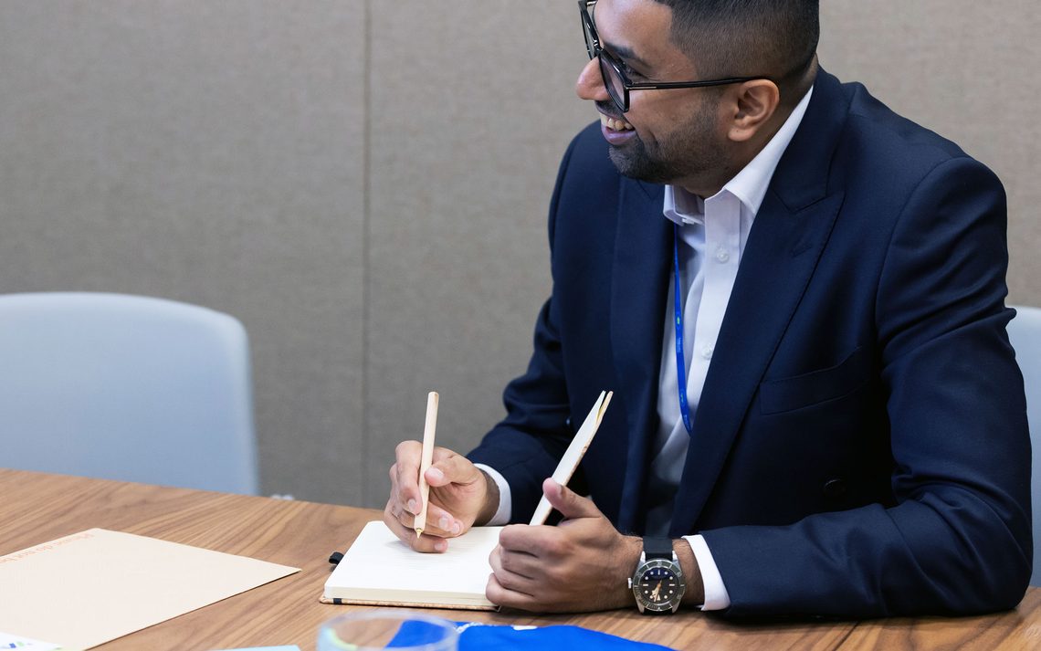 A Standard Chartered colleague smiles while taking notes at work