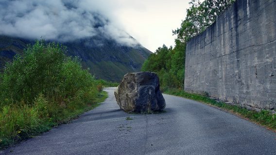 A boulder blocks a road.