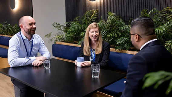 A group of Standard Chartered colleagues laugh together.