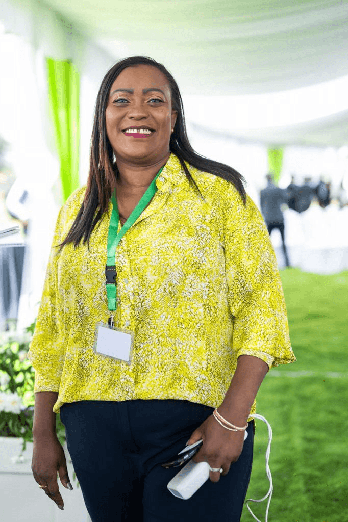 A smiling woman in a yellow shirt runs an event. 