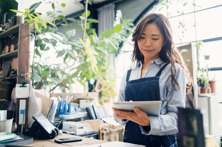 A woman works on her small business. She's using an iPad to explore financing solutions.