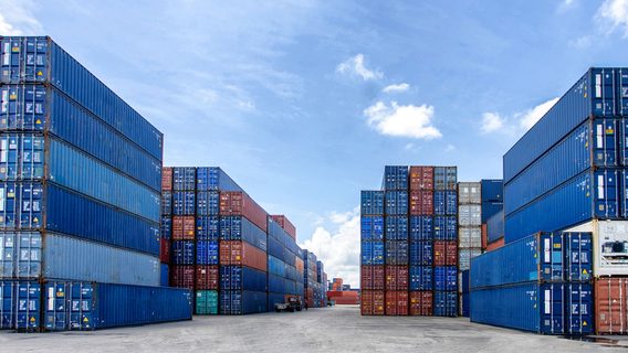 Blue shipping containers wait in a port