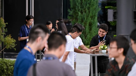 A group of people enjoying an outdoor event, gathered around a table filled with food and drinks.