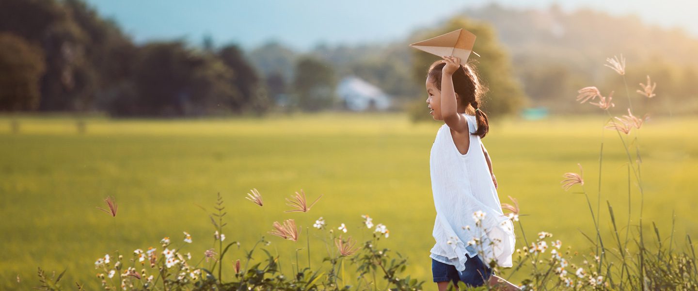 Young girl running through green field