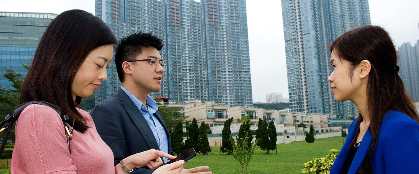 3 people having discussion in front of skyscrapers
