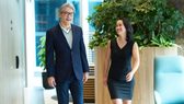Two experienced career professionals walk down the hallway in a Standard Chartered office.