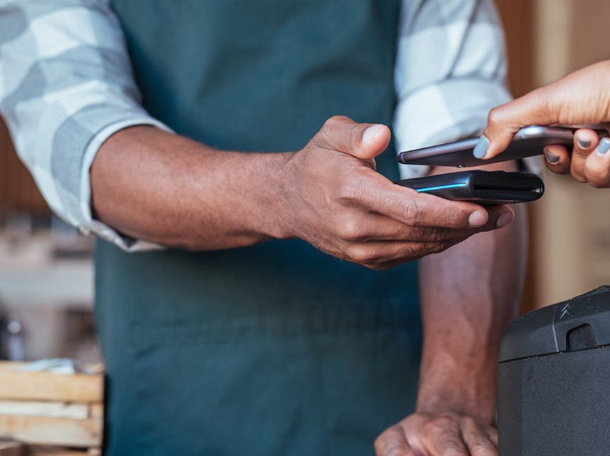 Someone uses contactless payment to pay in a cafe.