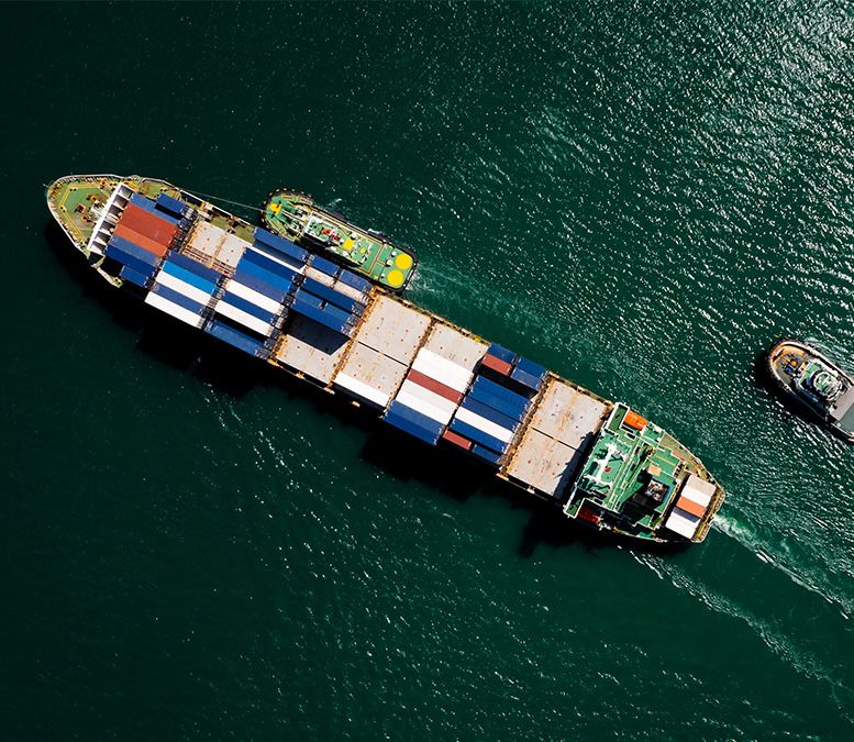 A container ship sails across a green sea.