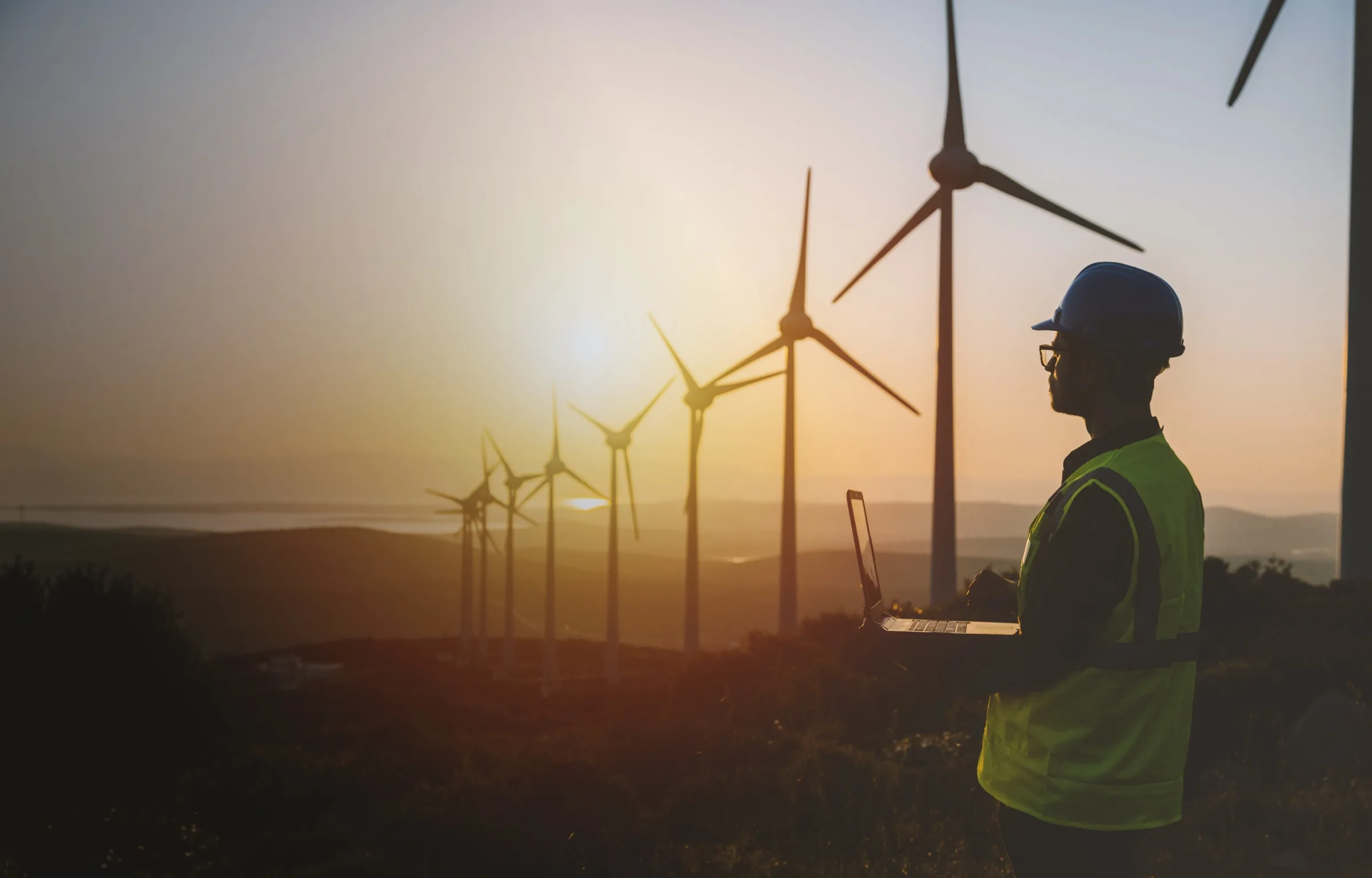 Man with laptop in an open field with windmills
