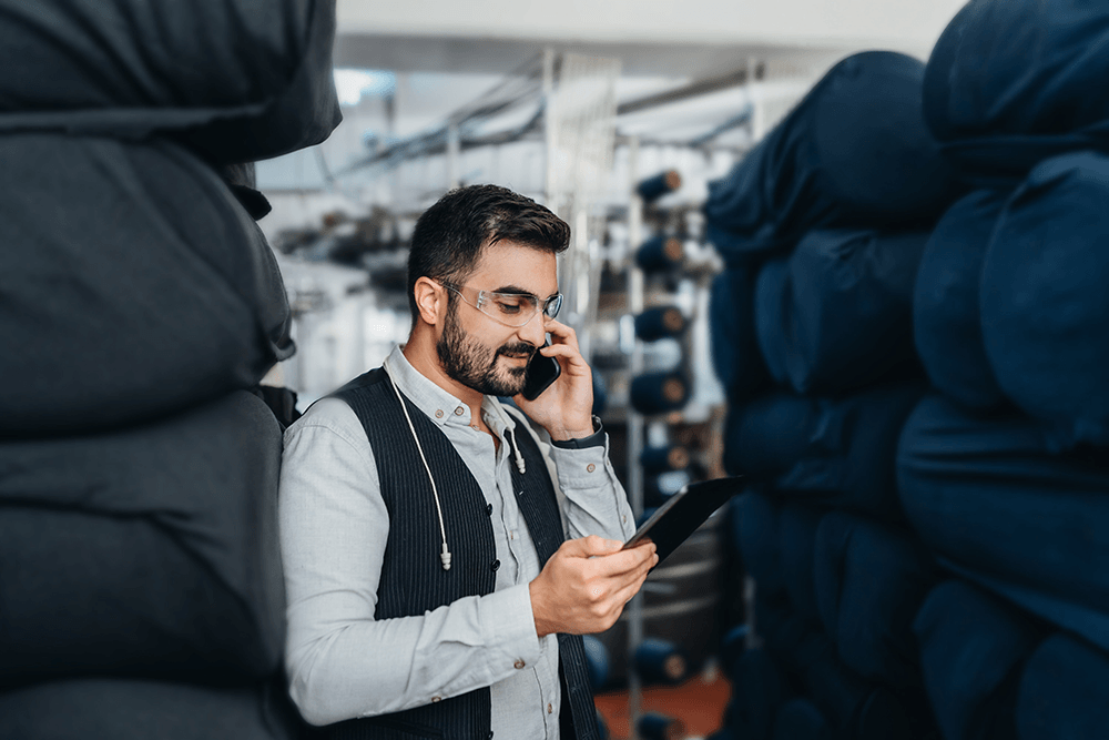 A man on phone and holding ipad