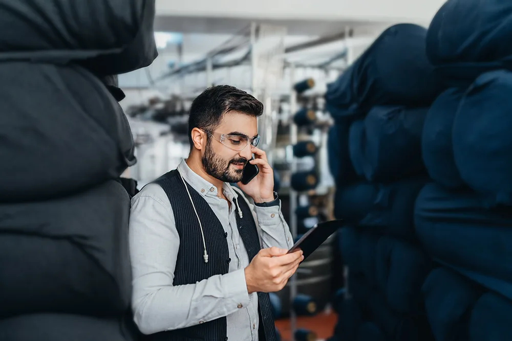 A man on phone and holding ipad