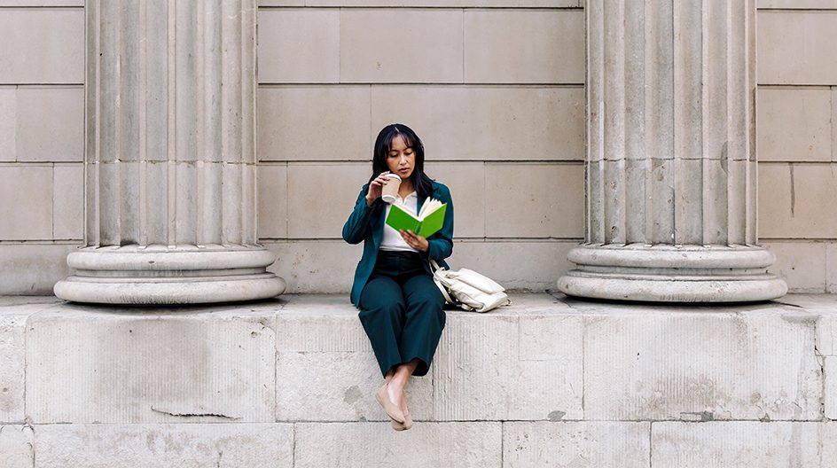 A woman reads a book on the Bank of England.