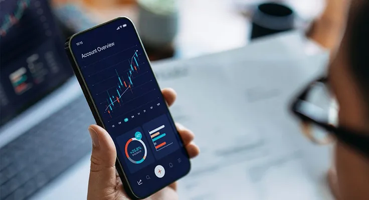 A corporate leader reviews economic trends on a mobile phone in the context of global trade digitilisation.