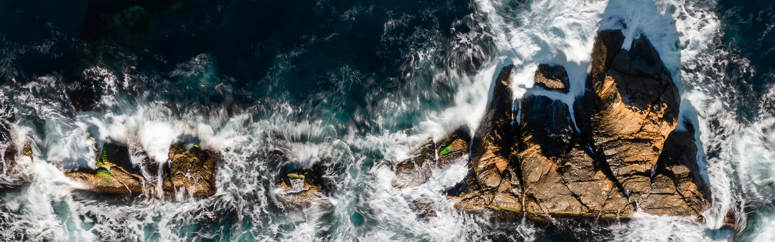 Waves hit rocks on the shoreline.