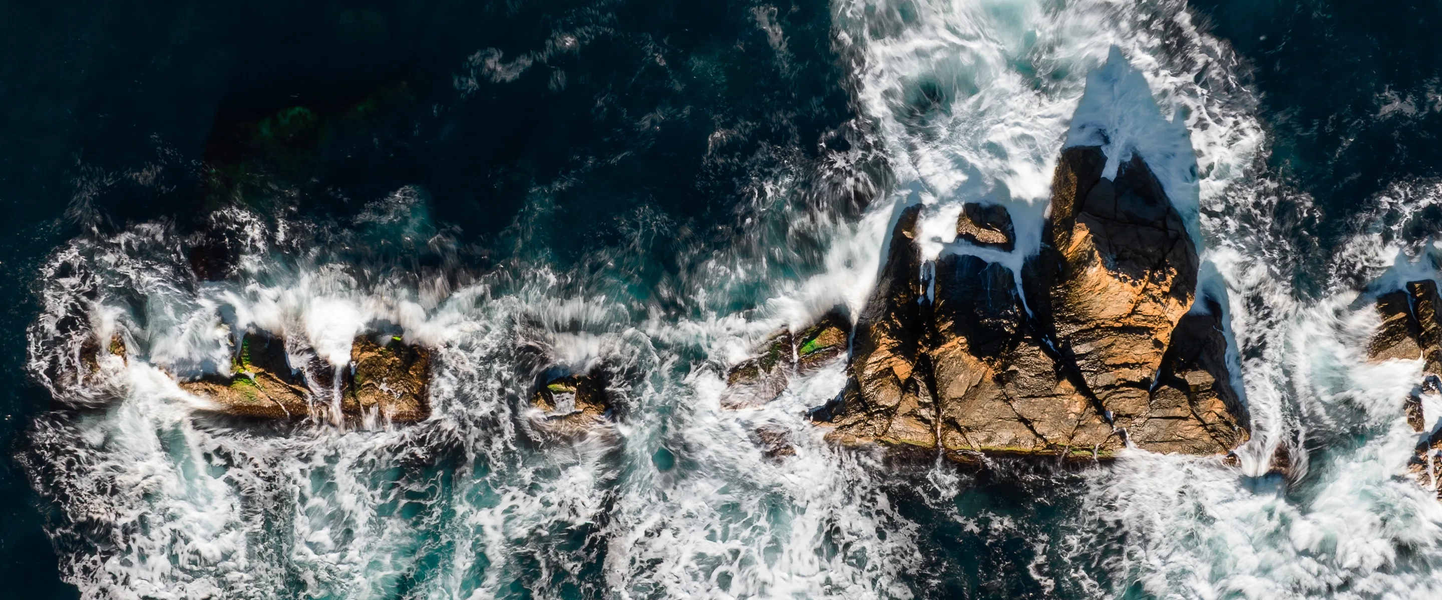 Waves hit rocks on the shoreline.