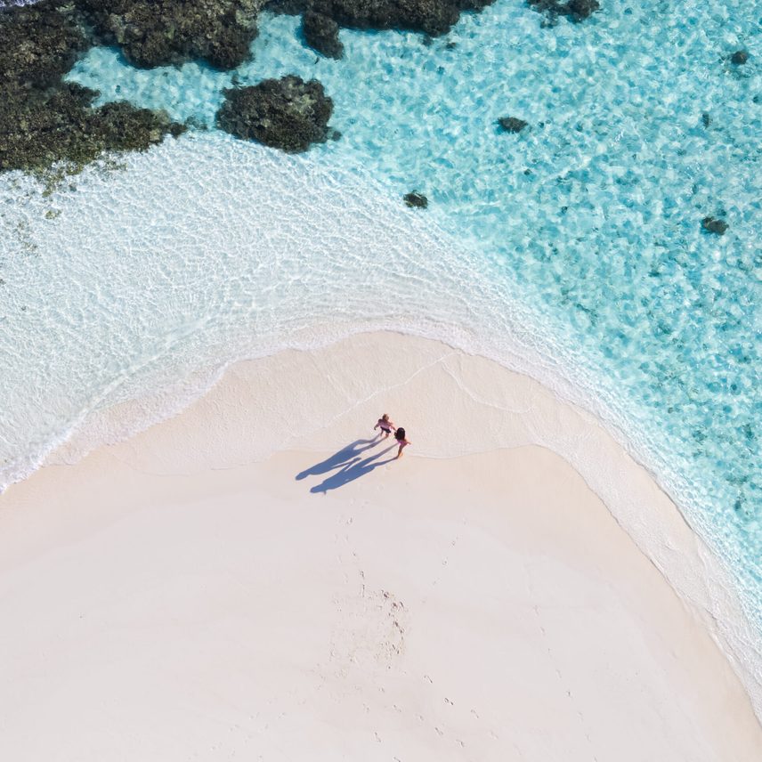 drone view of adult couple on a beach, maldives