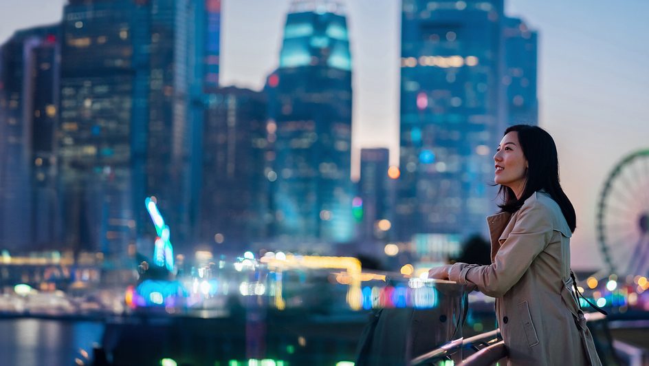 A smiling woman looks out over a cityscape.
