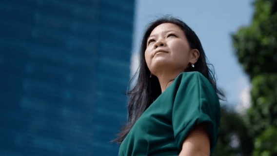 A low angle shot of a woman standing in front of her office building