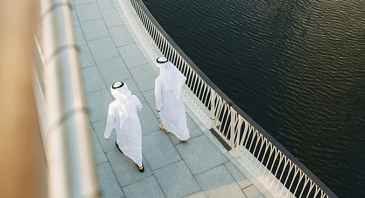 Two business colleagues walk across a bridge together.