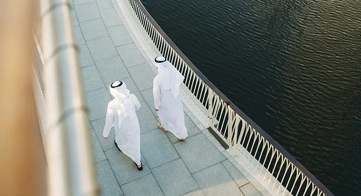 Two business colleagues walk across a bridge together.