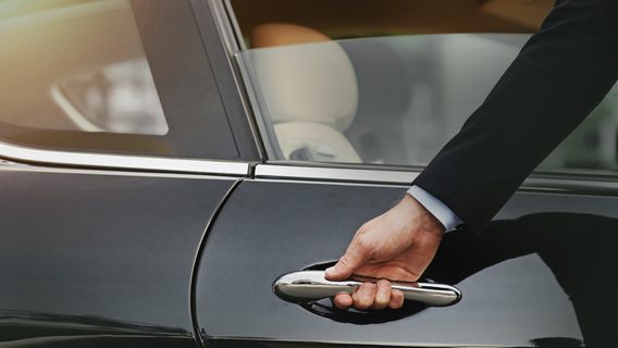 A chauffeur prepares to open the door of a limousine for a Standard Chartered Private Bank client.