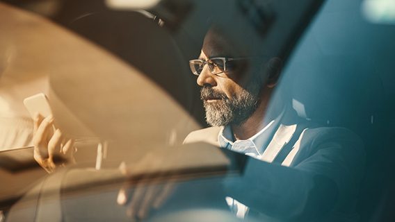 A passenger in a car reads his emails on a phone