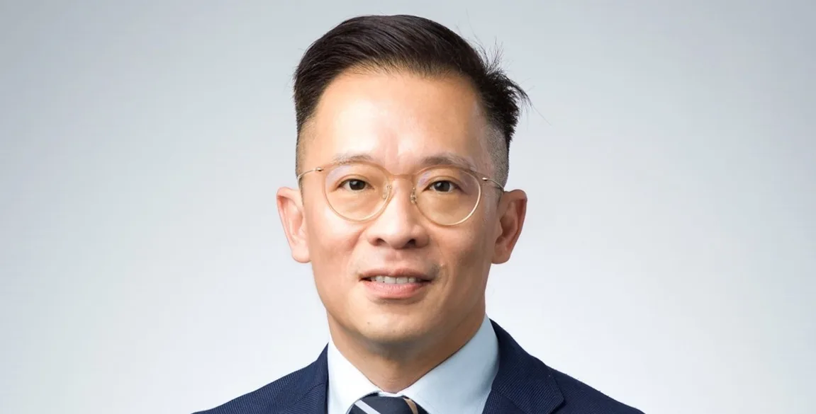 A smiling man in a suit with glasses.