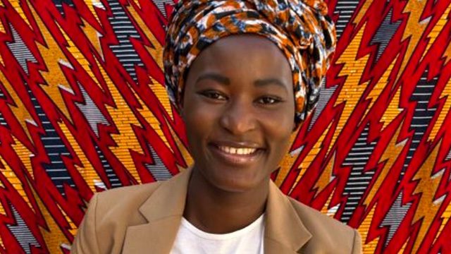 Naomi poses in front of a cloth screen.