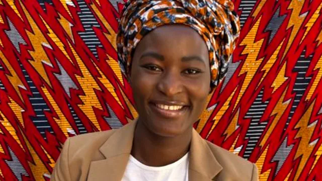 Naomi poses in front of a cloth screen.