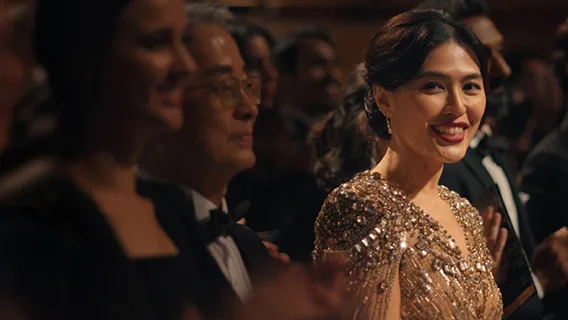 A woman in a sequined gold dress smiles at the camera.