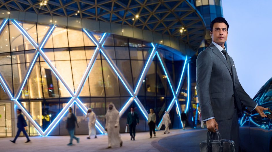  A man in a suit stands beside a luxury car