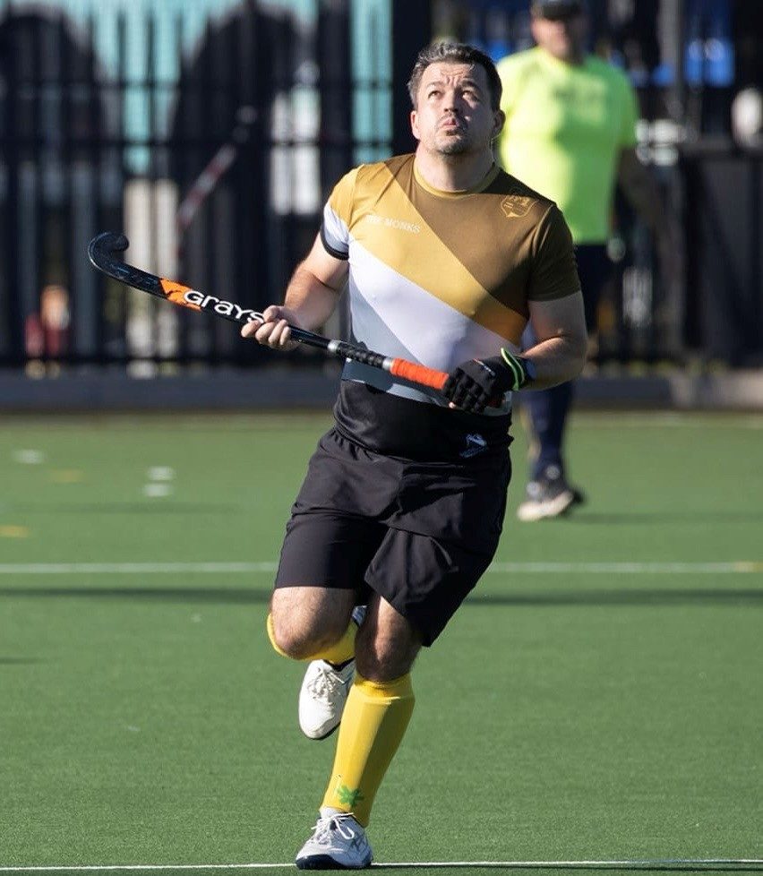 An action shot depicting Peter Cousins competing at the Asian Championships in Hong Kong alongside the Singapore National Masters Hockey Team (over 40s).