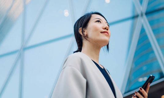 A woman in a city holding a mobile phone.