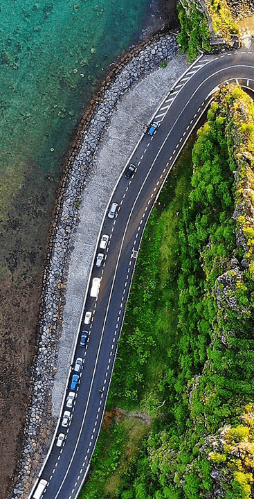 Aerial view of a road with forest on one side and sea on the other