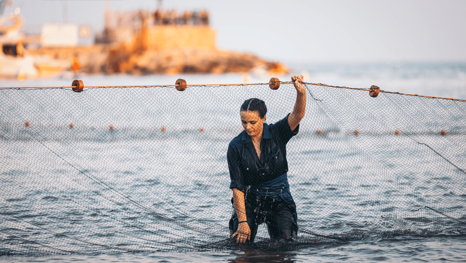 A woman pulls a fishing net out of the water