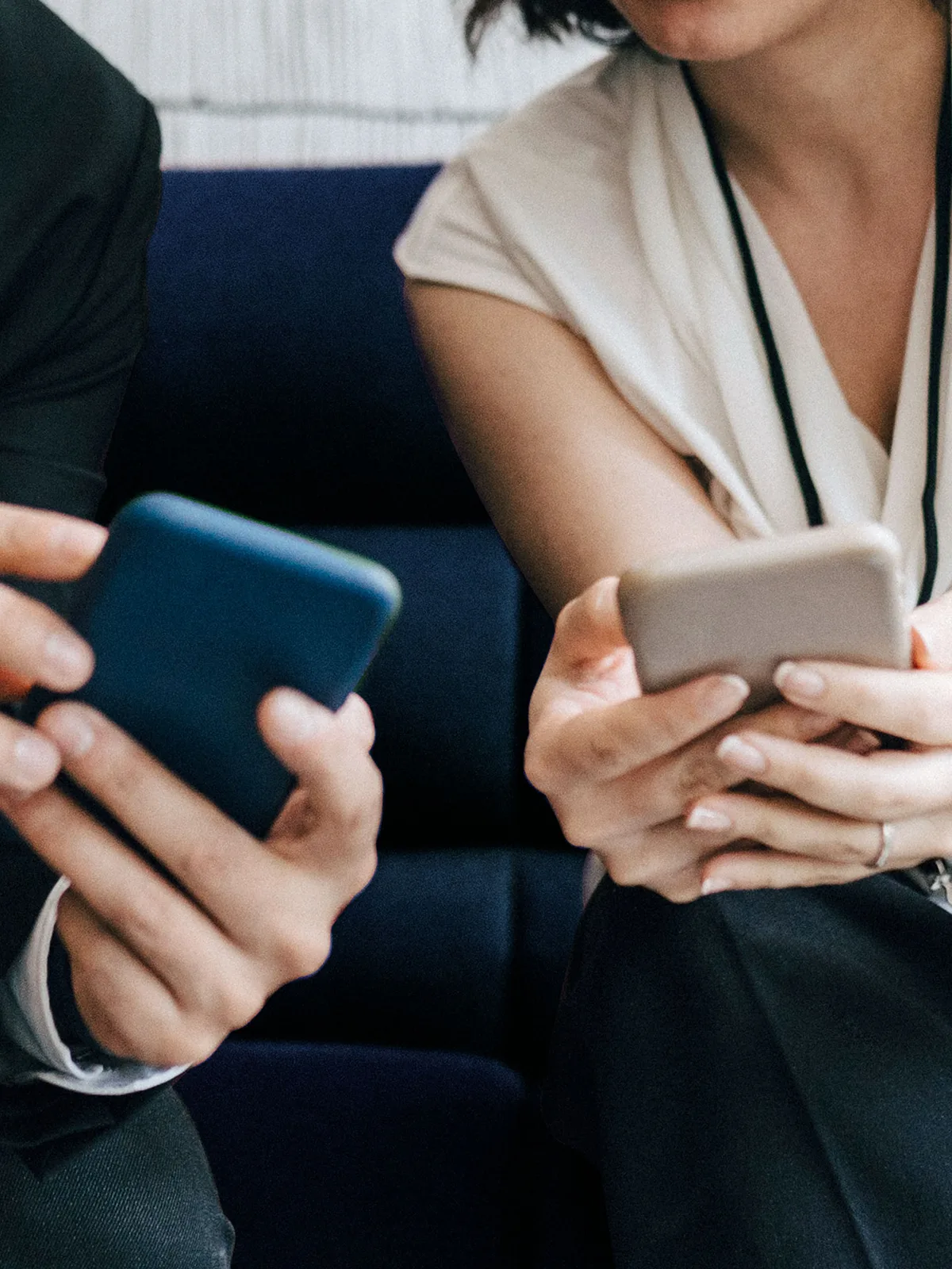 Two colleagues look at social media content on mobile phones.