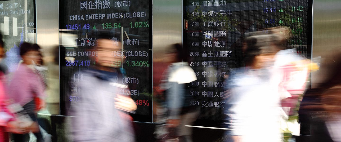 people walking past stocks boards