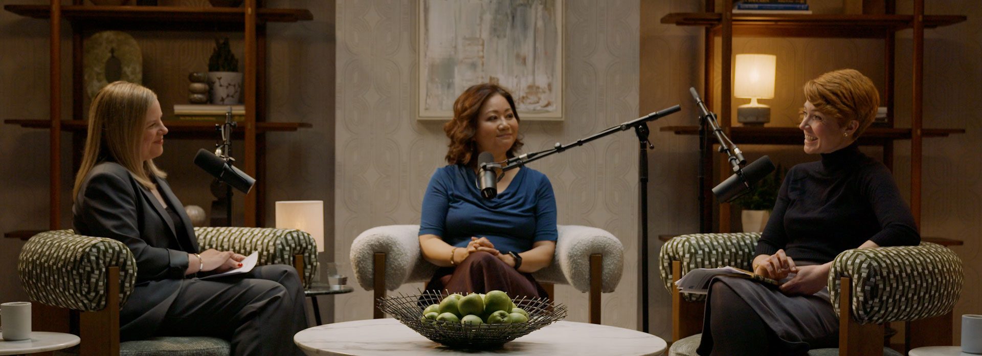 Three women in a podcast studio having a friendly conversation during Episode 2.