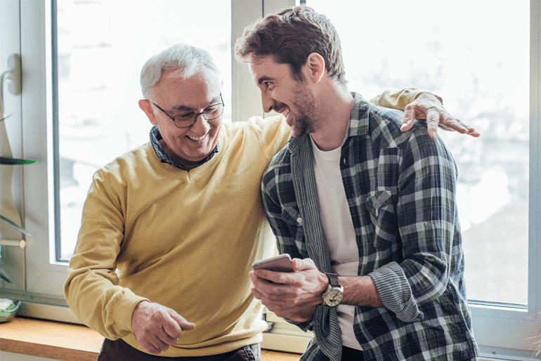 Father and son watching phone and hugging