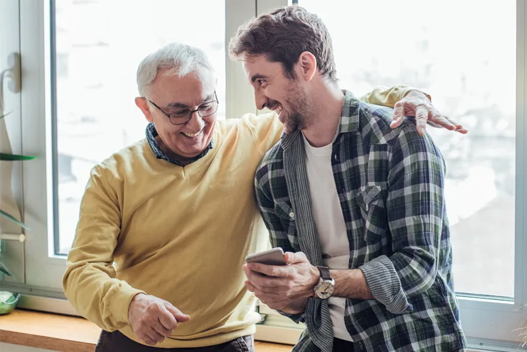 Father and son watching phone and hugging