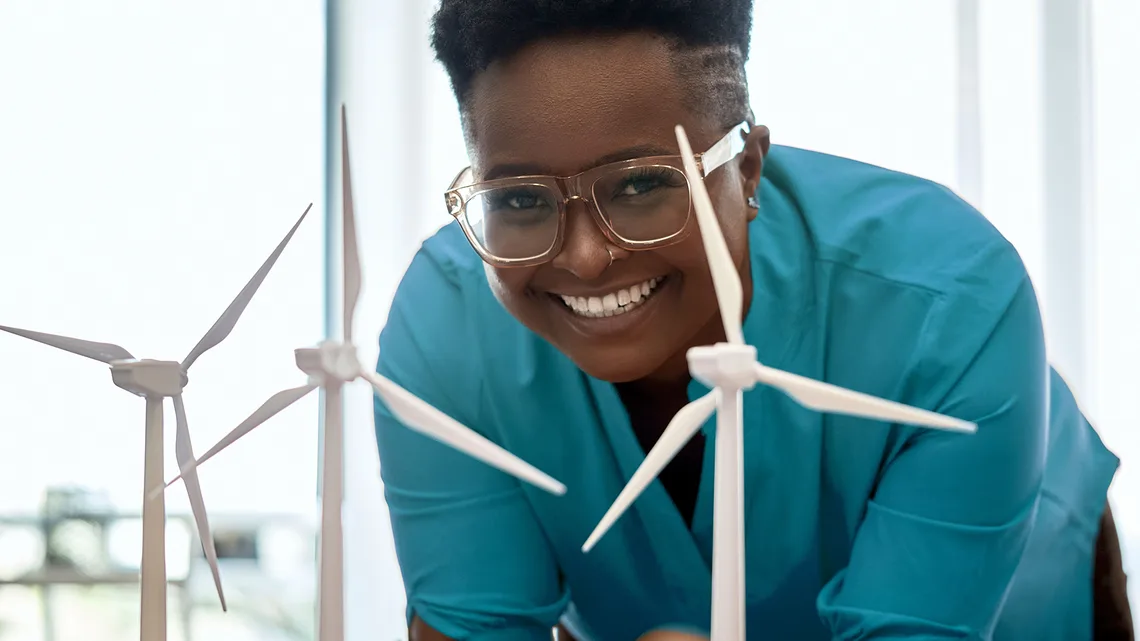 A woman smiles in front of some model wind turbines.