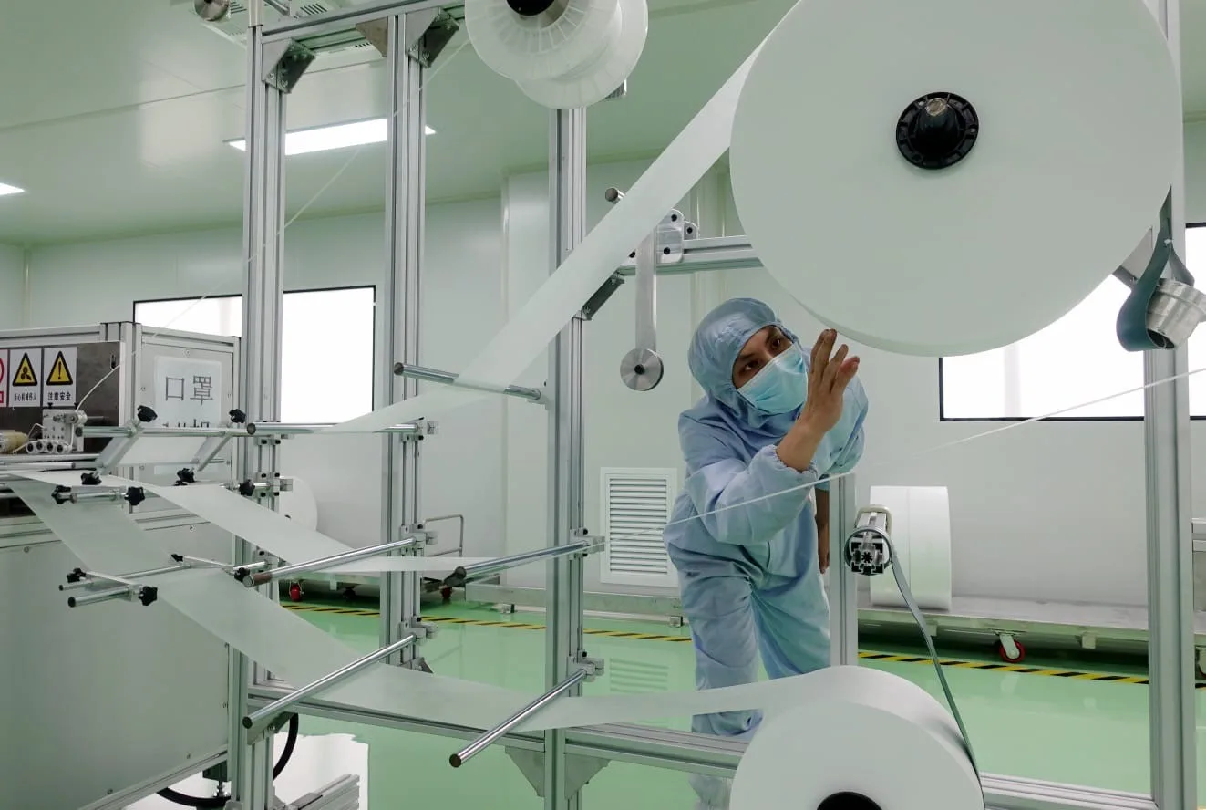 person in face mask and hair net inspecting machine