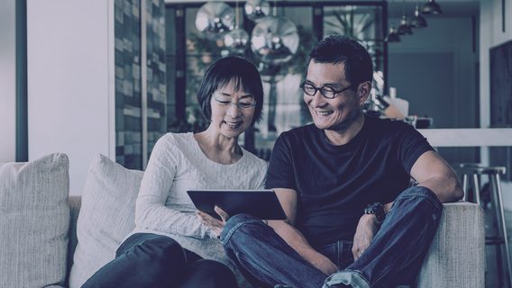 Couple smiling at tablet sitting together