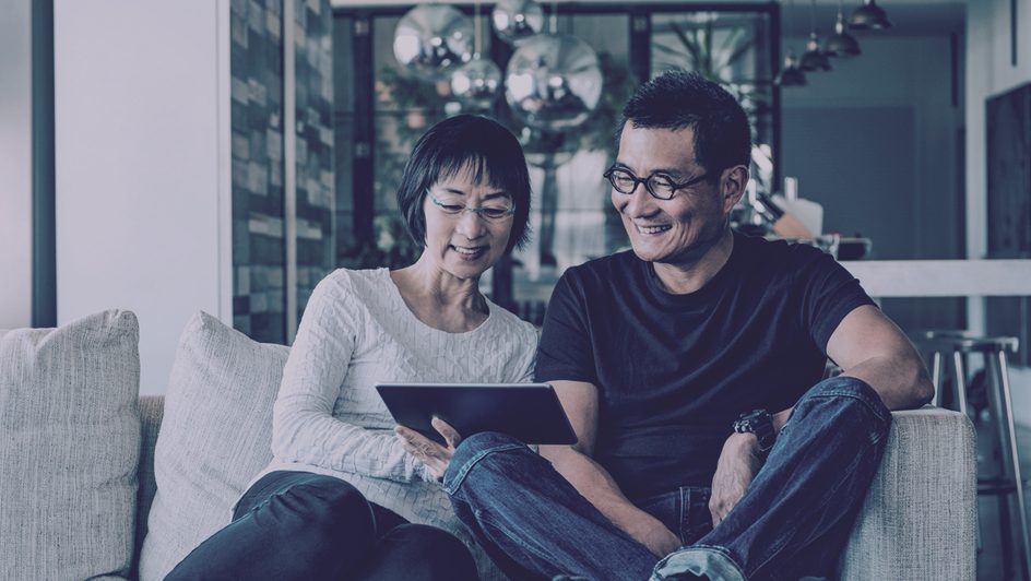 Couple smiling at tablet sitting together