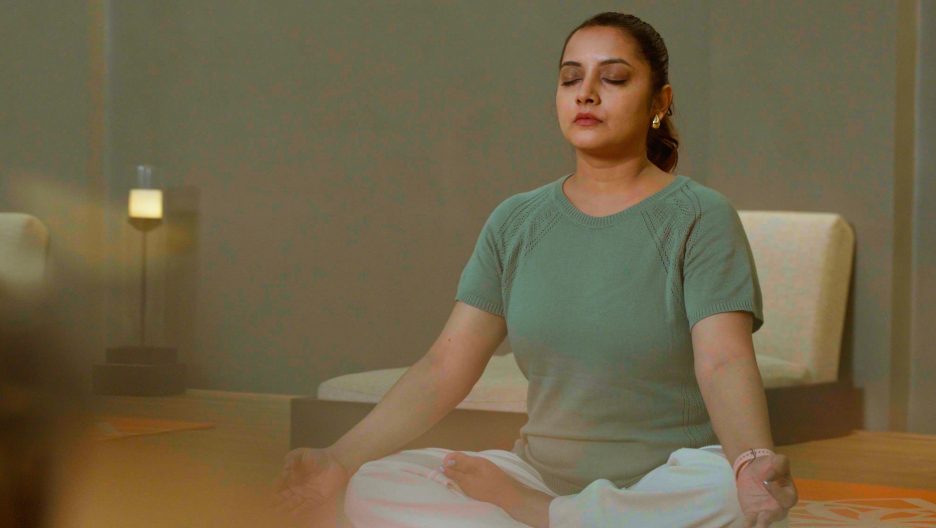 A woman in a yoga class, eyes closed, meditating calmly