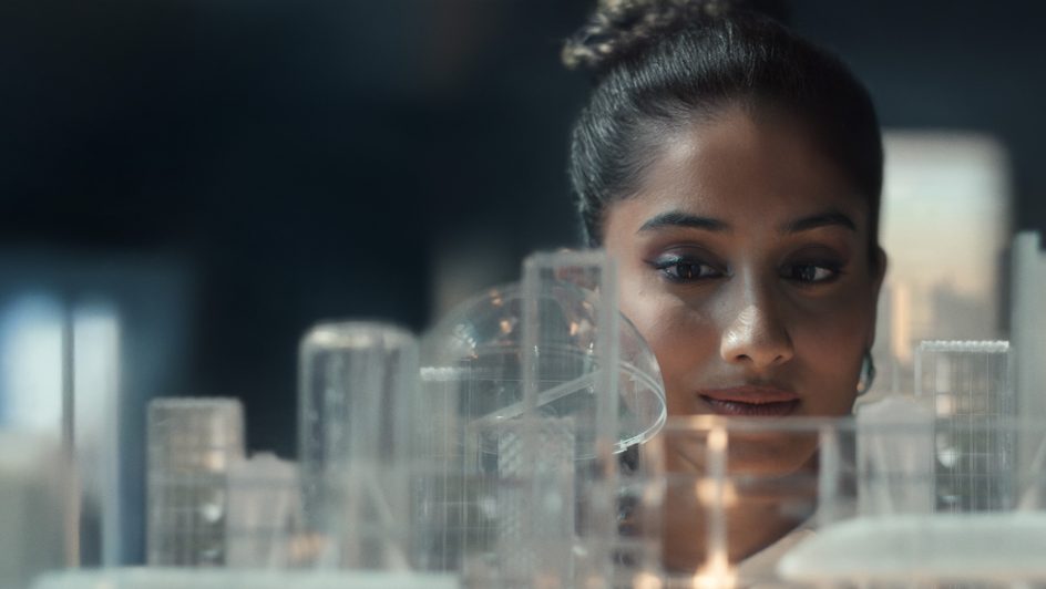 A woman gazes at a city skyline while holding a lit candle, creating a serene and contemplative atmosphere.
